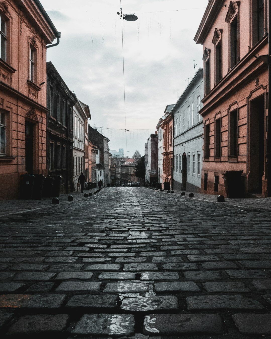 Foggy cobblestone street in Zagreb's Upper Town at night with a single glowing lamp post