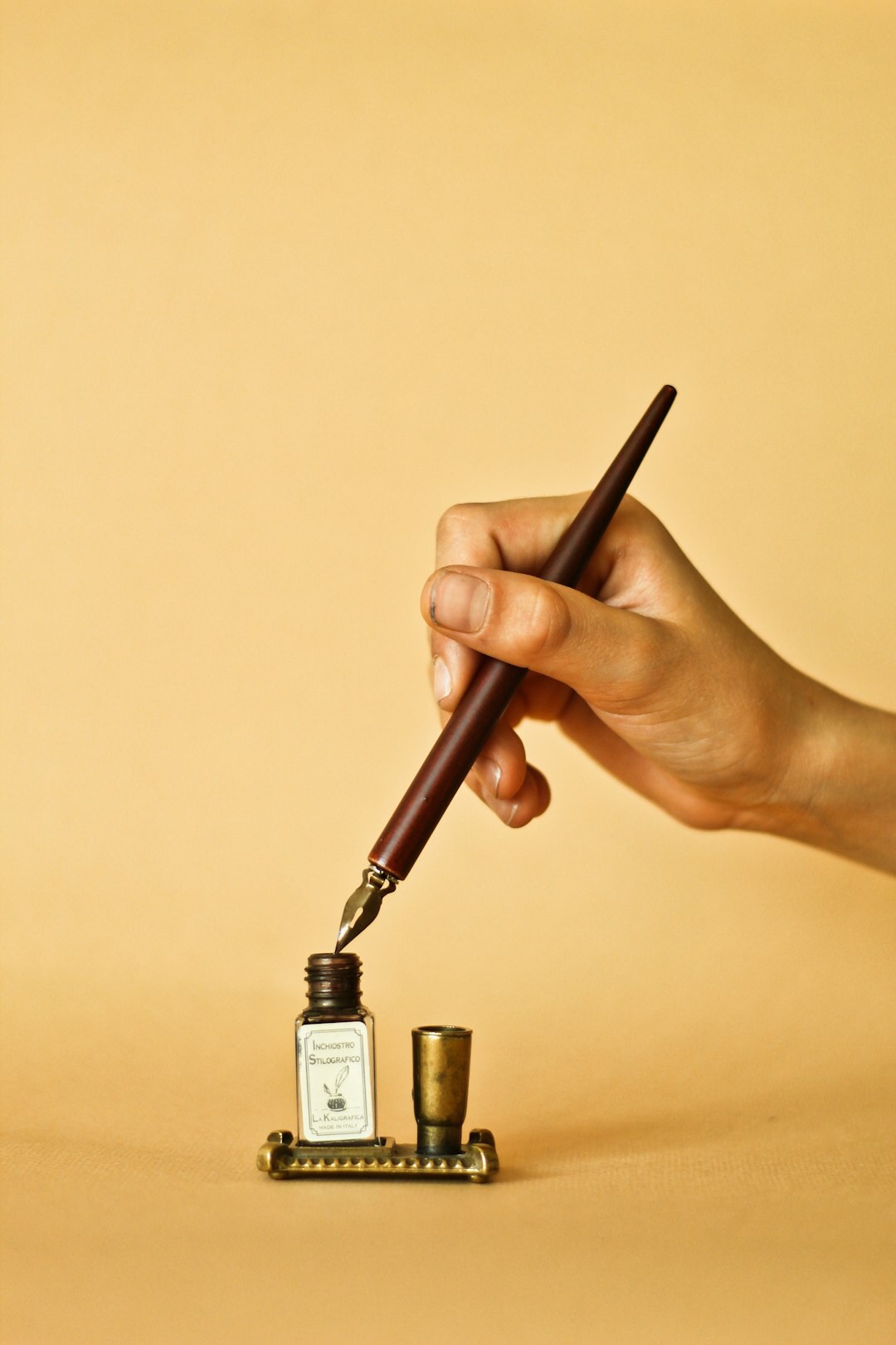 Close-up of hands writing with a fountain pen in a notebook on a wooden desk