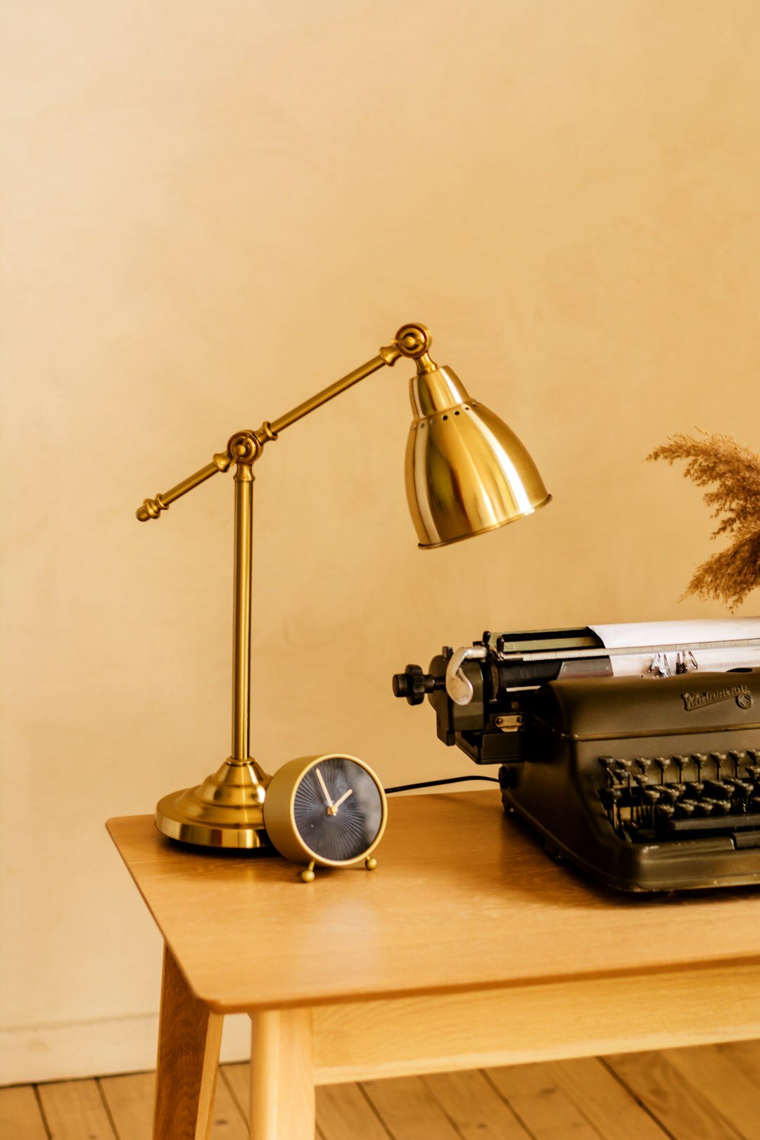 Wooden writer's desk with a vintage typewriter, notebook, and cup of coffee lit by a desk lamp
